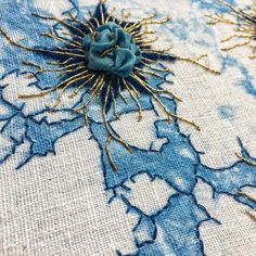 blue and gold embroidered fabric with flowers on the side, in close up view to the center