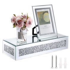 there is a vase with flowers on top of the table next to a mirror and screws