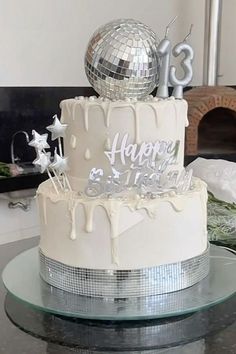 a white cake with silver decorations and a disco ball on top