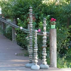 a wooden walkway with rocks and flowers on the posts, along with a fence in the background