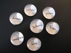 six glass buttons with words written on them