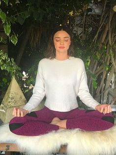 a woman is sitting in the middle of a meditation pose