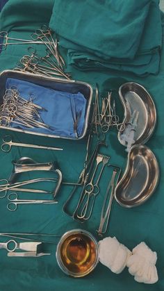 an assortment of medical utensils are laid out on a green tablecloth with silverware