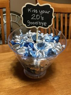 a glass bowl filled with blue and white candies on top of a wooden table