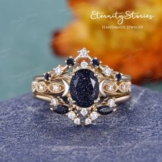 a blue and white diamond ring sitting on top of a piece of stone with an orange flower in the background