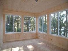 an empty room with large windows and wood paneling