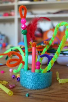 a cup filled with lots of different colored pens and pencils on top of a wooden table