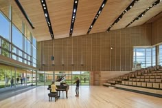 two people standing in front of a piano on top of a hard wood floor next to an auditorium