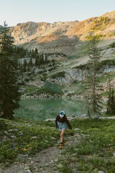 a person walking up a trail towards a lake