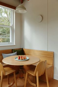 a table with some fruit on top of it in front of a bench and window