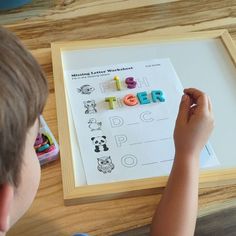 a young boy sitting at a table working on letters and numbers with magnets in front of him