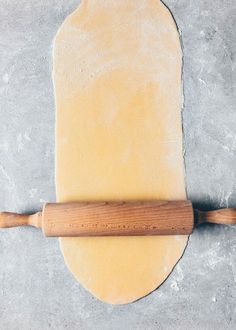 a wooden rolling pin on top of a dough