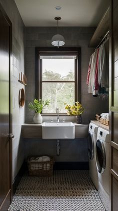 a washer and dryer in a bathroom with a window above the sink, next to a laundry basket