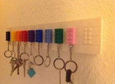 a row of lego key chains hanging on a white wall with keys attached to it