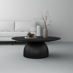 a living room with a couch, table and vase on the floor in front of it