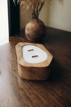 an electronic device sitting on top of a wooden table next to a vase with flowers