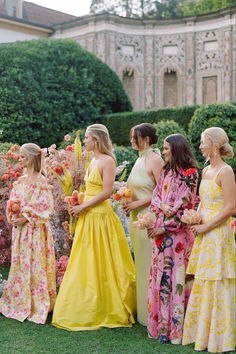 a group of women standing next to each other on top of a lush green field