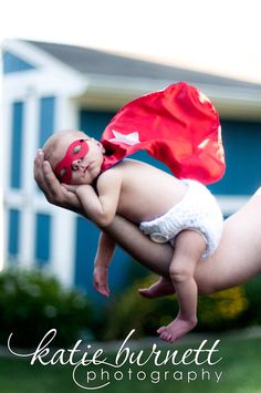 a woman holding a baby in her arms and wearing a red cape on top of it's head