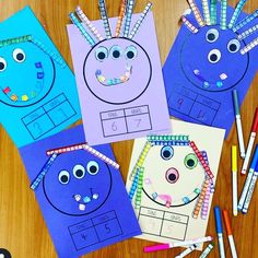 four blue and purple paper cut out to look like faces with pencils on the table