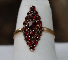 Antique Estate Bohemian Gypsy multi GARNET RING 14k  size 6 (1) approximately 5mm Faceted Center Stone, Garnet Cabochon ..Multi Prong Set and Some Prongs Shared with  (2) Faceted Garnets  approximately 4mm  flanking center Stone and Prong Set (16) approximately:  2 mm Faceted Garnets ... Shared Prong Set... Surrounding the Outer Edge (2) mm Shank Measuring approximately : 7/8"  X  3/8" Tested: 14K Yellow Gold 2.1 grams You are welcome to send an offer for an item… Gemstones color might vary slightly according to computer screens. I have photographed these pieces in Hawaiian light and they may appear slightly different in another environment. Due to the difference in Rates, I might not be able to combine shipping internationally. Please check with me before bidding.   I cannot check every c Garnet Ring Vintage, Antique Jewelry Rings, Garnet Ring, Ring Pictures, Garnet Rings, Elegant Accessories, Ring Vintage, Gemstone Colors, Vintage Watches