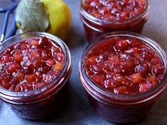 three jars filled with fruit sitting on top of a table