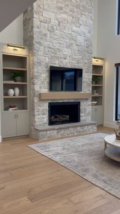 a living room with a large stone fireplace and built - in shelving units on either side