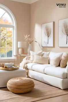 A serene living room with neutral decor, featuring a white sofa with cozy pillows, a woven pouf, a stylish coffee table with a tray, and elegant wall art. The room is bathed in natural light from a large window. Bright And Airy Living Room, Beach House Vibes, Accent Chair Decor, Cozy Neutral Living Room, Coastal Neutral, House Vibes, Neutral Home Decor, Neutral Room, Living Room Design Ideas