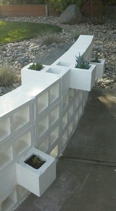 a white concrete wall with plants growing in it