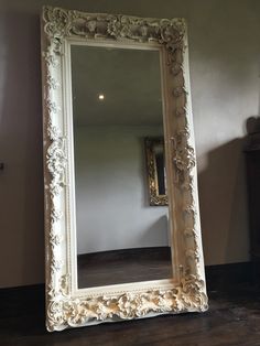 a large white mirror sitting on top of a wooden floor