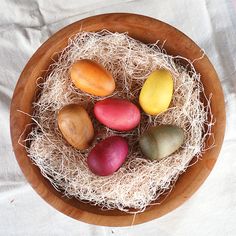 a wooden bowl filled with different types of fruit on top of a white table cloth