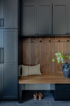 a wooden bench sitting in the middle of a room next to cupboards and shoes