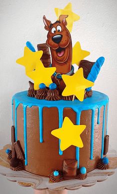 a birthday cake decorated with stars and a dog on top that is dripping in blue icing