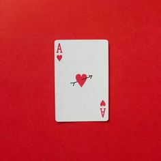 a playing card with hearts and arrows on the side, sitting on a red surface