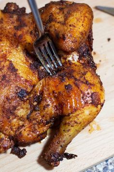 a close up of a chicken on a cutting board with a fork