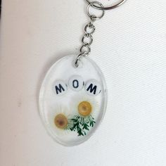 a glass keychain with two dandelions and the word mom on it