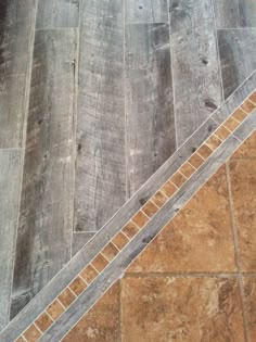 an orange cat is sitting on the floor next to a stair case and some tiles