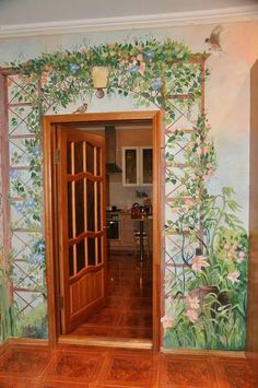 an open door leading into a kitchen with flowers painted on the walls and wood floors