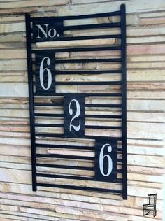 a metal sign that says no 6 and two numbers on it, mounted to the side of a wooden wall