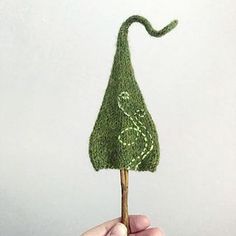 a hand holding a miniature green tree on a stick