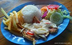 a blue plate topped with lots of food on top of a wooden table