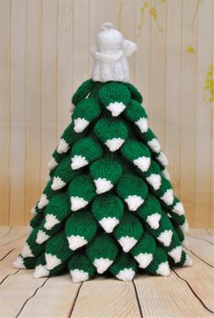 a knitted christmas tree with white and green hearts on the top, sitting on a wooden floor