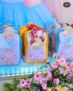 three princess luggage bags sitting on top of a table next to flowers and vases