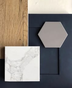 some different types of tile on top of a wooden floor next to a white and gray wall