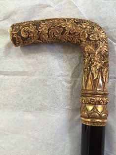 an ornate gold and black handle on a wine bottle with white paper in the background