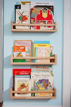 two wooden shelves with books on them against a blue wall