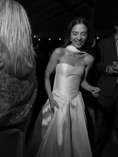 a black and white photo of a woman in a wedding dress smiling at someone else