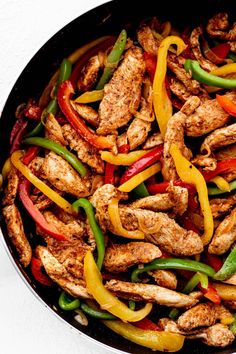 chicken and peppers in a skillet on a white surface