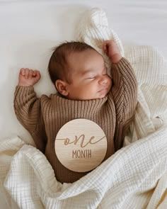 a baby wrapped up in a blanket with the word me month on it's chest