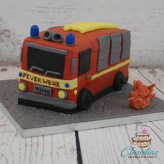 a cake shaped like a firetruck is sitting on a table next to an orange flower