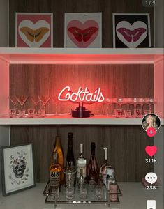 a shelf with bottles and glasses on top of it next to two framed pictures that say cocktails